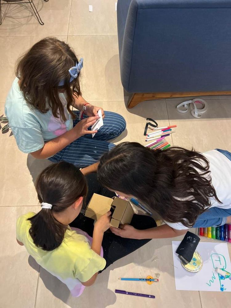 Las tres integrantes trabajando en el piso con cartón y plumones
